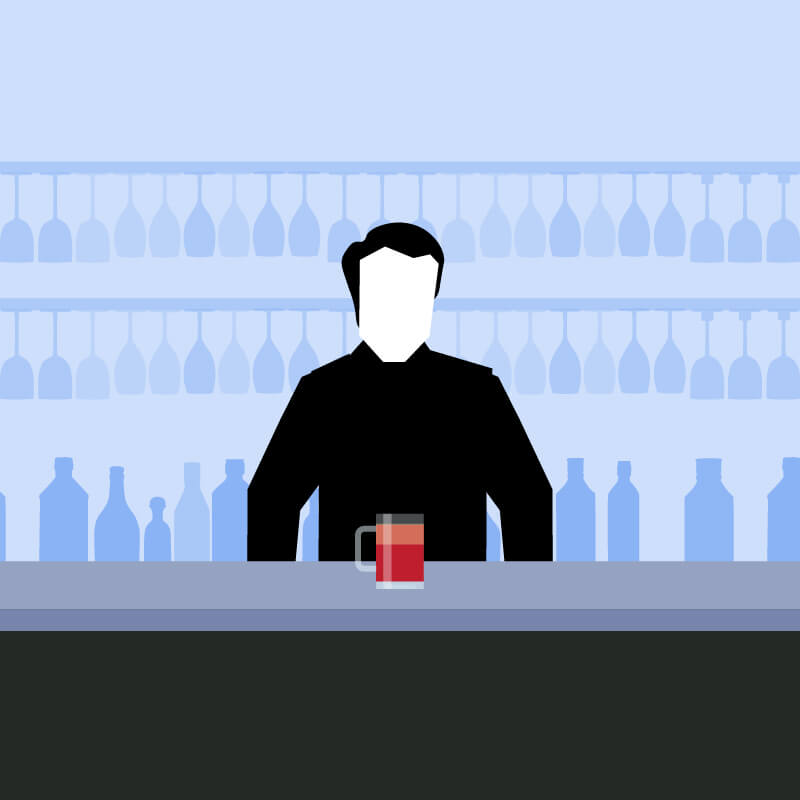 Man standing behind a drinks bar with a red cocktail in front of him