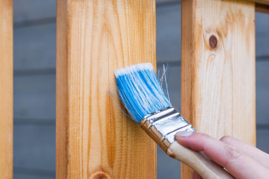 someone using a brush on wood showing how to clean wooden garden furniture